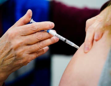 A health worker administers a dose of a COVID-19 vaccine during a vaccination clini