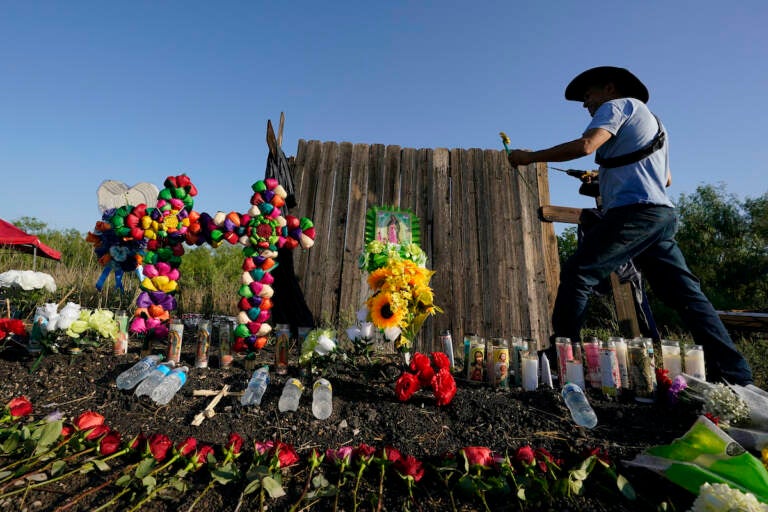 Roberto Marquez of Dallas adds a flower a makeshift memorial at the site where officials found dozens of people dead in an abandoned semitrailer containing suspected migrants, Wednesday, June 29, 2022, in San Antonio. (AP Photo/Eric Gay)