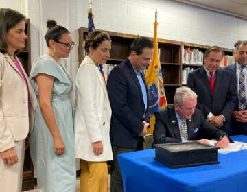 New Jersey Democratic Gov. Phil Murphy (seated) signs the $50.6 billion fiscal year 2023 budget, Thursday, June 30, 2022, in Cranford, N.J. The bill sets aside $2 billion for property tax relief and carries a nearly $7 billion surplus into the new year. Flanking the governor from left to right are state Treasurer Elizabeth Muoio, Assembly member Eliana Pintor Marin, state Senate Majority Leader Teresa Ruiz, Senate President Nicholas Scutari, Assembly Speaker Craig Coughlin and state Sen. Paul Sarlo. (AP photo/Mike Catalini), (