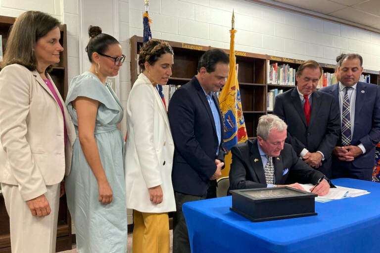 New Jersey Democratic Gov. Phil Murphy (seated) signs the $50.6 billion fiscal year 2023 budget, Thursday, June 30, 2022, in Cranford, N.J. The bill sets aside $2 billion for property tax relief and carries a nearly $7 billion surplus into the new year. Flanking the governor from left to right are state Treasurer Elizabeth Muoio, Assembly member Eliana Pintor Marin, state Senate Majority Leader Teresa Ruiz, Senate President Nicholas Scutari, Assembly Speaker Craig Coughlin and state Sen. Paul Sarlo. (AP photo/Mike Catalini), (