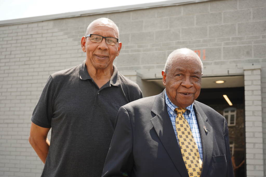 Former Chester Mayor John Linder stands next to Garland Thompson in front of a gray brick building.