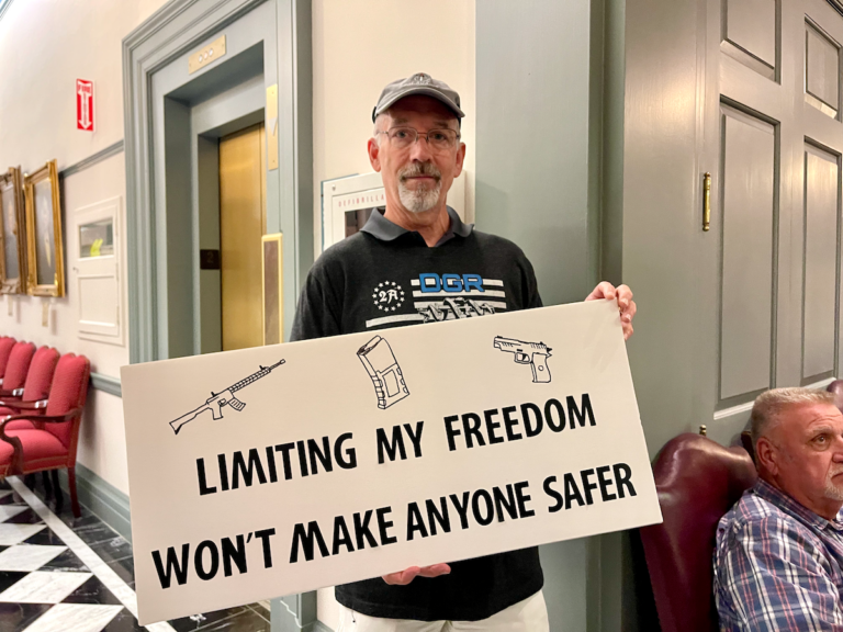 File photo: Brent Burdge of Wilmington, Delaware displays his sign in protest to the passing of legislation outside of Gov. John Carney's office. (Johnny Perez-Gonzalez/WHYY)