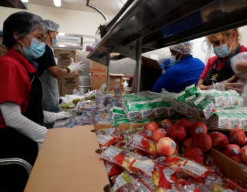 Service workers pre-package hundreds of free school lunches in plastic bags. (Damian Dovarganes/AP)