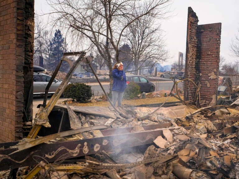 A woman reacts to seeing the remains of her mother's home destroyed by the Marshall Wildfire in Louisville