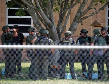 Law enforcement personnel stand outside Robb Elementary School following a shooting on May 24 in Uvalde, Texas. When the gunman arrived at the school, he hopped its fence and easily entered through an unlocked back door, police said. (Dario Lopez-Mills/AP)