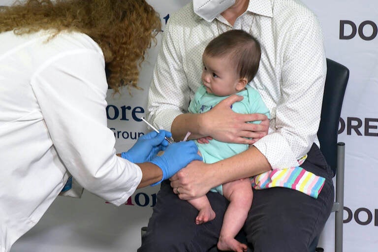 Ellen Fraint holds her daughter, 7-month-old Jojo, as she receives the first dose of the Moderna COVID-19 vaccine.