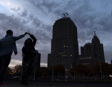 People dance in Detroit as the sun sets behind the skyline in November 2020. (David Goldman/AP Photo)