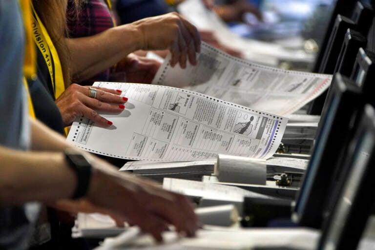 Close-up of election workers' hands handling ballots.