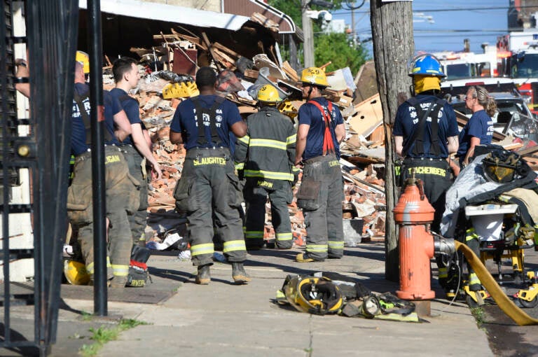 Firefighters survey the scene of a building collapse at N. 3rd St and W. Indiana Ave. in the city's Fairhill section where a 27-year veteran firefighter died. (Jonathan Wilson for Billy Penn)