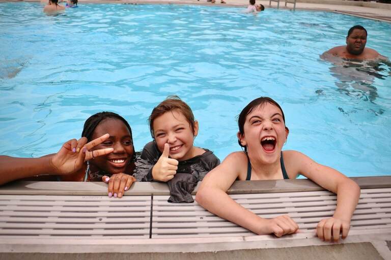 Melonie Shamlin, 10, Melody Sheridan, 9, and Isabella Prall, 10, celebrate their first swim at the new Lederer Pool in Fishtown. (Emma Lee/WHYY)