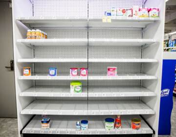 Empty shelves in a store where normally baby formula would be stocked.