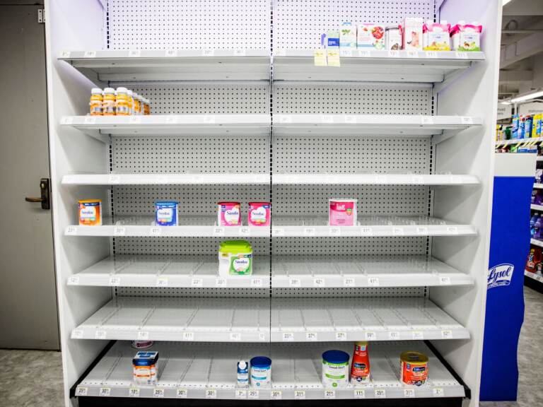 Empty shelves in a store where normally baby formula would be stocked.