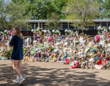 A young woman pays her respects at a memorial in front of Robb Elementary School earlier this monthin Uvalde, Texas. Committees have begun inviting testimony from law enforcement authorities, family members and witnesses regarding the mass shooting at Robb Elementary School which killed 19 children and two adults. (Brandon Bell/Getty Images)