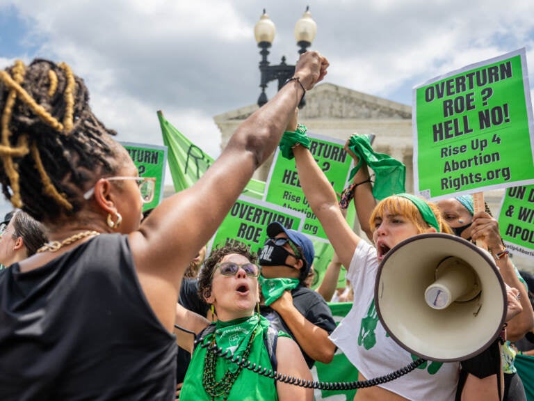 Abortion rights activists clad in green and carrying green signs protest outside the Supreme Court