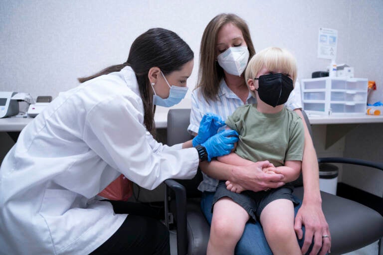 Pharmacist Kaitlin Harring, left, administers a Moderna COVID-19 vaccination to 3-year-old Fletcher Pack