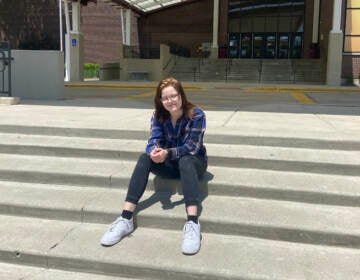 A high school student sits on the steps of Schamburg High School in Illinois.