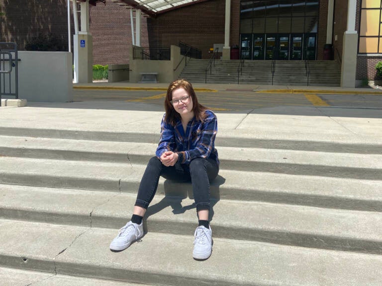 A high school student sits on the steps of Schamburg High School in Illinois.