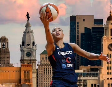 The Mystics' Natasha Cloud lifts up a basketball with the Philadelphia skyline in the background.