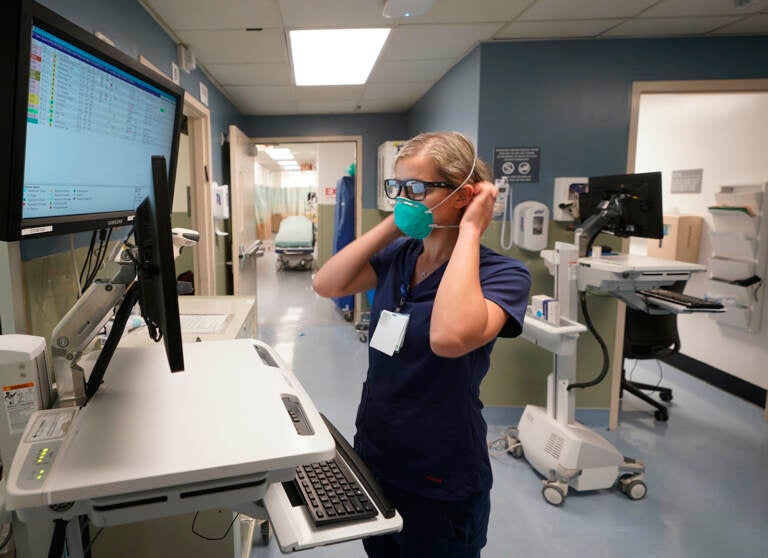 Sandra Younan adjusts her N95 face mask as she checks her patients records at the emergency room