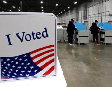 An ''I Voted'' decal is seen in the foreground, as voters cast their ballots in the background