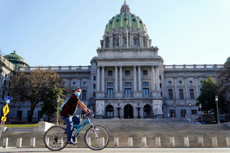 A cyclist rides past the Pennsylvania Capitol