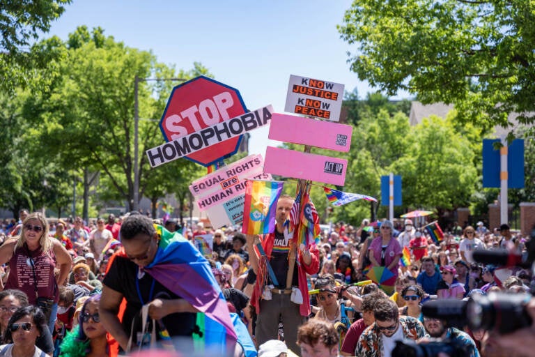 A man holds signs encouraging equal rights, Black Lives Matter, and stopping homophobia.