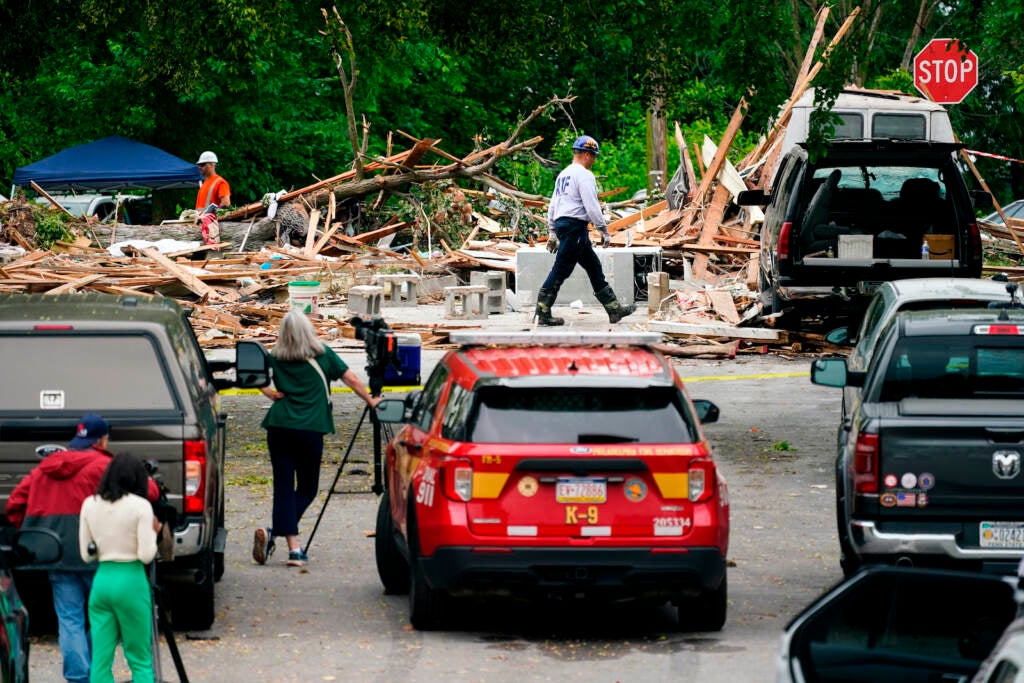 An investigator, center top, moves through the scene of a deadly explosion in a residential neighborhood in Pottstown