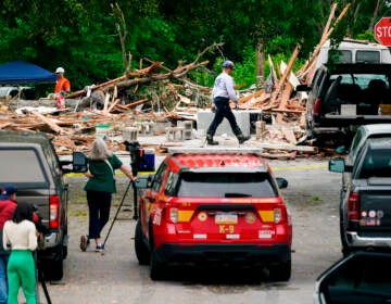 An investigator, center top, moves through the scene of a deadly explosion in a residential neighborhood in Pottstown