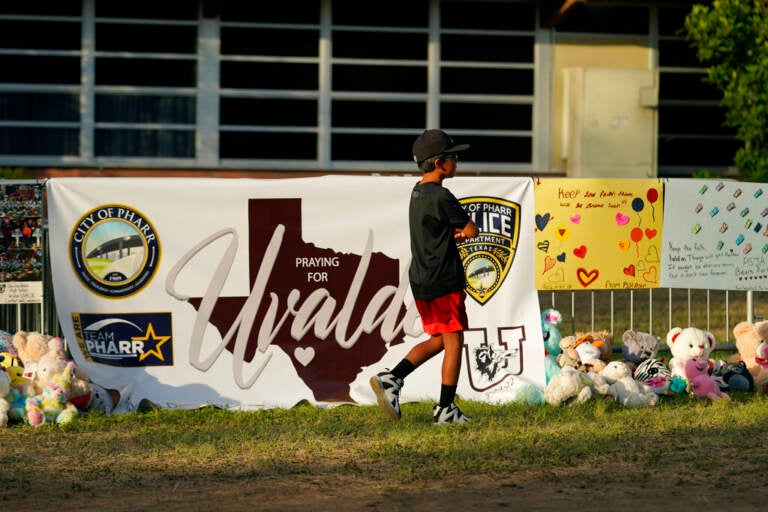 A boy walks in front of a memorial to the victims of the mass shooting in Uvalde, Texas.
