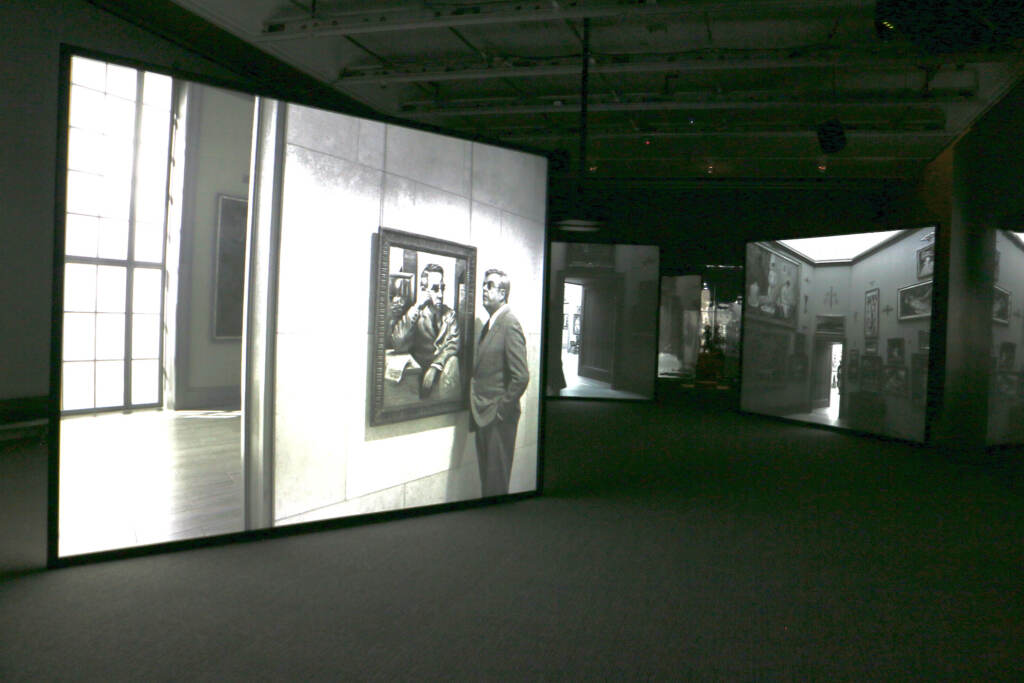 An immersive film installation at The Barnes, with one panel showing Albert Barnes studying an image of himself.