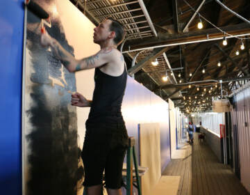 Sean Dooley, a first time participant in the Tiny Room for Elephants art festival, prepares his canvas at the Cherry Street Pier. (Emma Lee/WHYY)