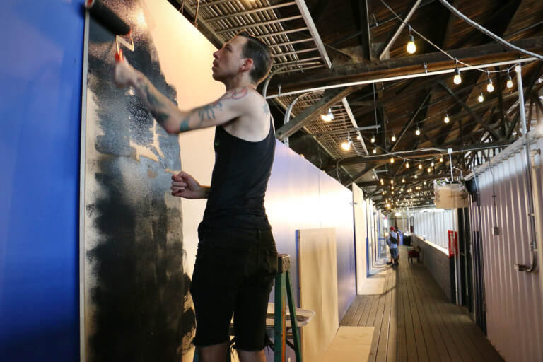 Sean Dooley, a first time participant in the Tiny Room for Elephants art festival, prepares his canvas at the Cherry Street Pier. (Emma Lee/WHYY)