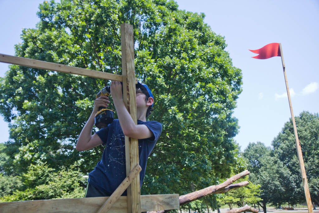 Noah Drury uses a power tool on a wood project at FDR Park