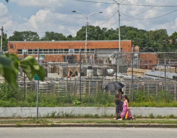 A woman uses an umbrella for protection from the sun in Juniata Park