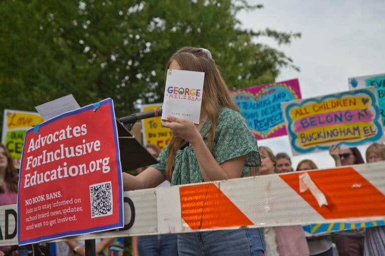 Lilly Freeman holds up a that helped her transition at a rally ahead of the Central Bucks School District’s vote to remove books perceived to have sexualized content from their libraries