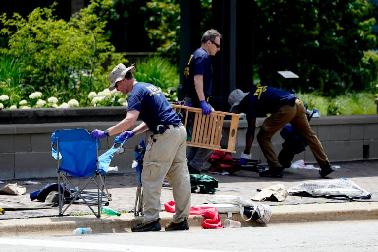 Members of the FBI's evidence response team remove personal belongings one day after a mass shooting in downtown Highland Park, Ill., Tuesday, July 5, 2022. (AP Photo/Charles Rex Arbogast)