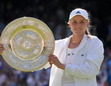 Kazakhstan's Elena Rybakina holds the trophy as she celebrates after beating Tunisia's Ons Jabeur to win the final of the women's singles on day thirteen of the Wimbledon tennis championships in London, Saturday, July 9, 2022. (AP Photo/Kirsty Wigglesworth)