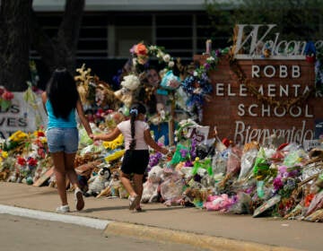 Visitors walk past a makeshift memorial honoring those recently killed at Robb Elementary School, Tuesday, July 12, 2022, in Uvalde, Texas. (AP Photo/Eric Gay)