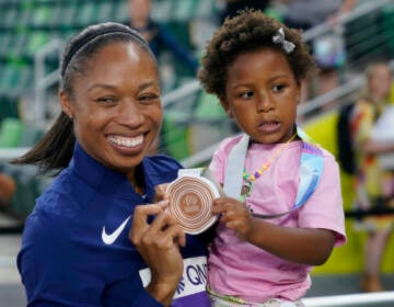 Allyson Felix, of the United States, gives her daughter Camryn her bronze medal after the 4x400-meter mixed relay final at the World Athletics Championships Friday, July 15, 2022, in Eugene, Ore. (AP Photo/Charlie Riedel)