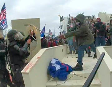 In this image from a Washington Metropolitan Police Department officer's body-worn video camera, and contained in the statement of facts supporting an arrest warrant for Mark Ponder, Ponder strikes an officer with a pole on the West Front of the U.S. Capitol on Jan. 6, 2021, in Washington. (Department of Justice via AP)