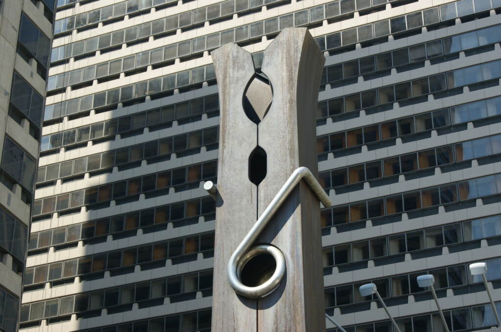 An up-close view of the top of the Clothespin sculpture, with a skyscraper visible in the background.