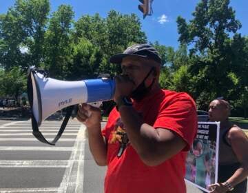 Jamal Johnson, from Germantown, protests outside Sesame Place on Saturday. Johnson and others aimed to raise awareness about what they say is discriminatory behavior from employees at the Bucks County theme park. (Emily Rizzo/WHYY)