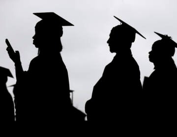 Graduates line up before the start of a community college commencement