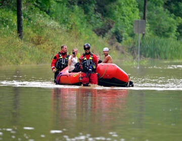 Search and rescue team is in a red boat in a flooded area.