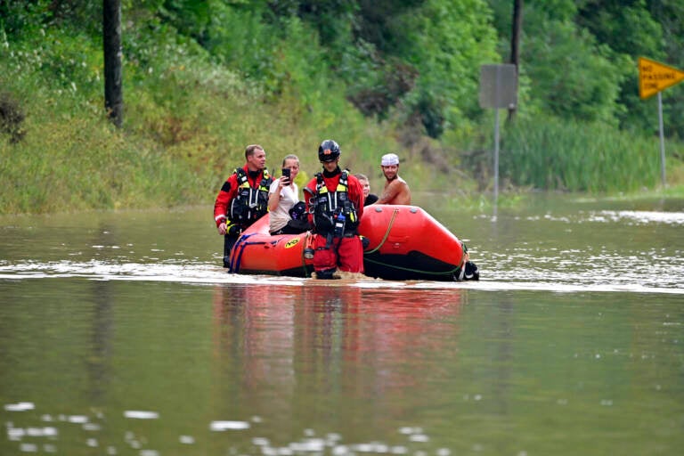 Search and rescue team is in a red boat in a flooded area.