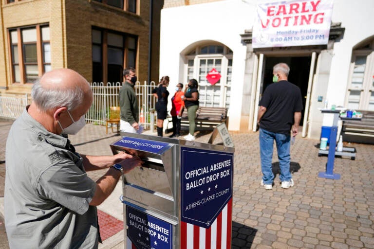 A man puts a ballot in a ballot drop box.