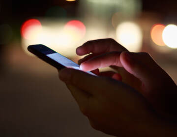 A close-up of a hand using a cell phone.