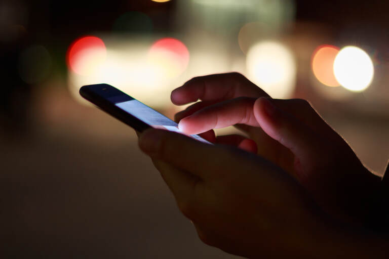 A close-up of a hand using a cell phone.