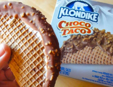 A person's hand holds up a Choco Taco