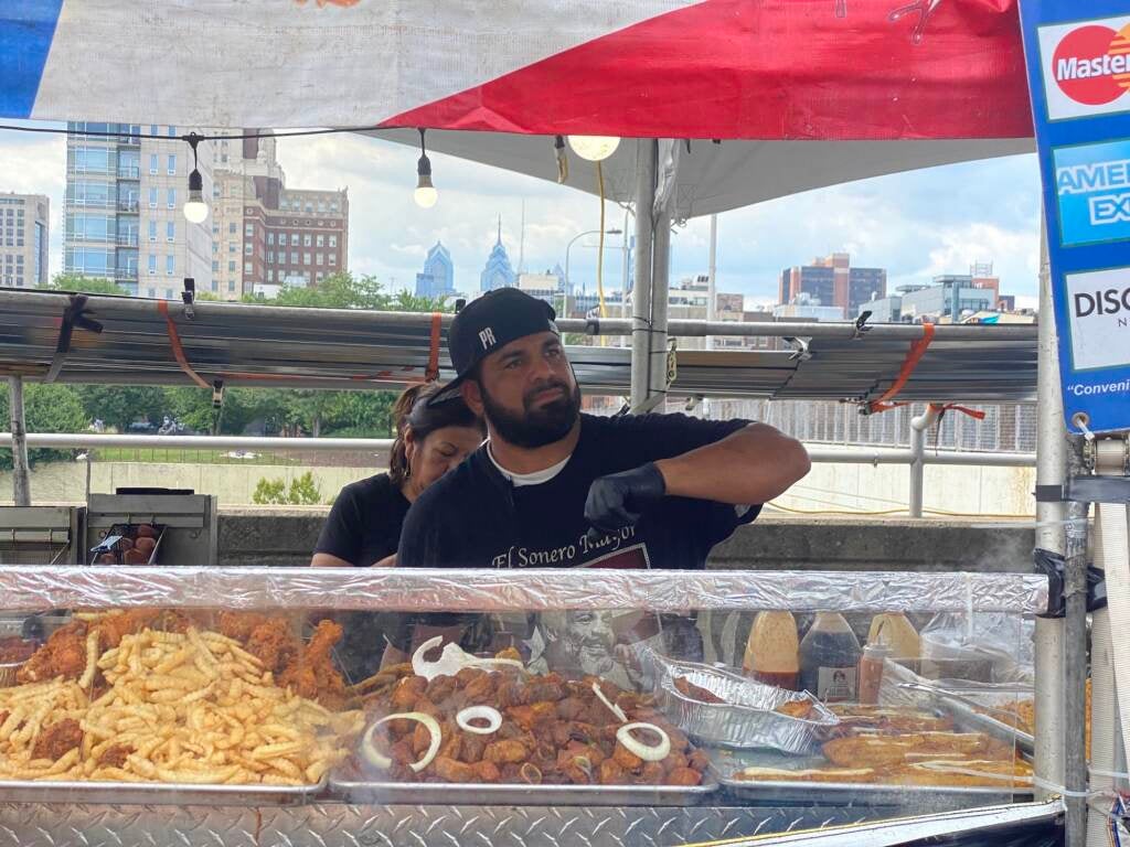 A chef looks over the countertop of his vendor station where he is selling food.